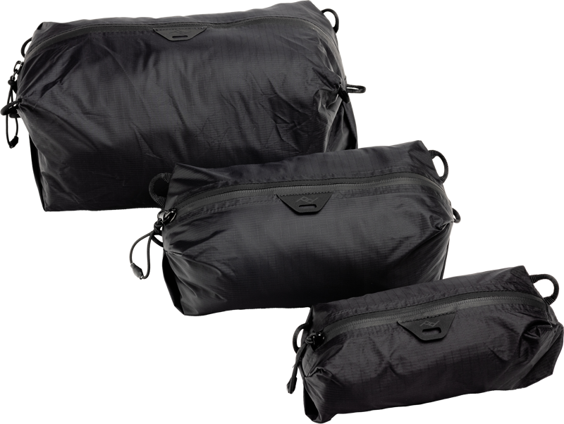 The black Peak Design Ultralight Packing Cube Bundle XXS-XS-S features three different sized zippered travel bags, each with a zippered flap and small handle, displayed on a light-colored background.