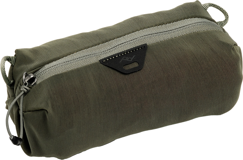 Peak Design Ultralight Mesh Packing Cube XX-Small in Sage on kompakti, oliivinvihreä vetoketjullinen pussi, jossa on kuvioitu kangas, sivulenkki ja musta kolmionmuotoinen logolaastari vetoketjun alla.