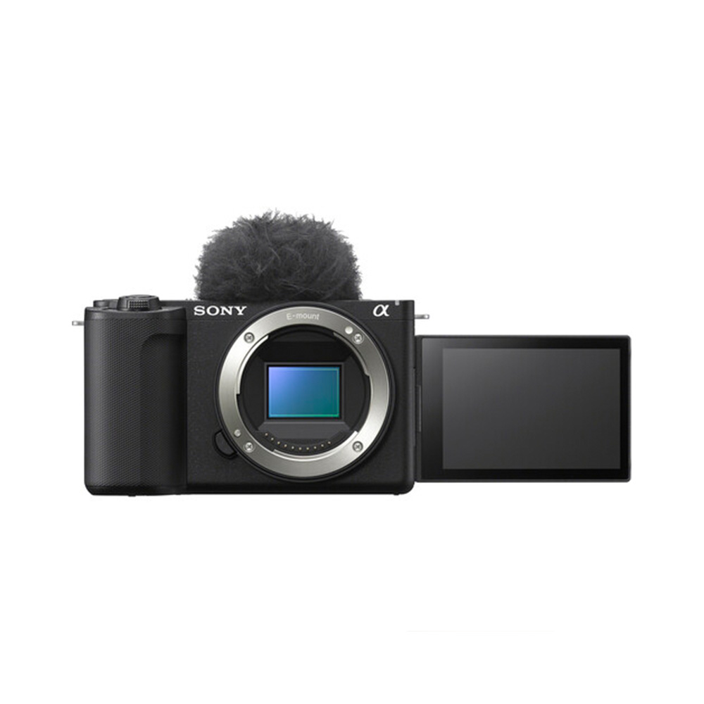 The Sony ZV-E10 II system camera, which has no lens, has a flip-out LCD screen and a fluffy microphone windscreen mounted on top, which is visible against a white background.