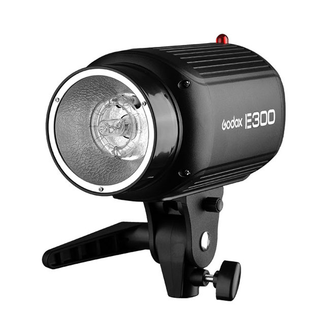 Musta Godox Studio Kit E300 F -studiosalama, jossa on sisäänrakennettu kahva ja säädettävä kiinnike, näkyy etupuolelta valkoista taustaa vasten.