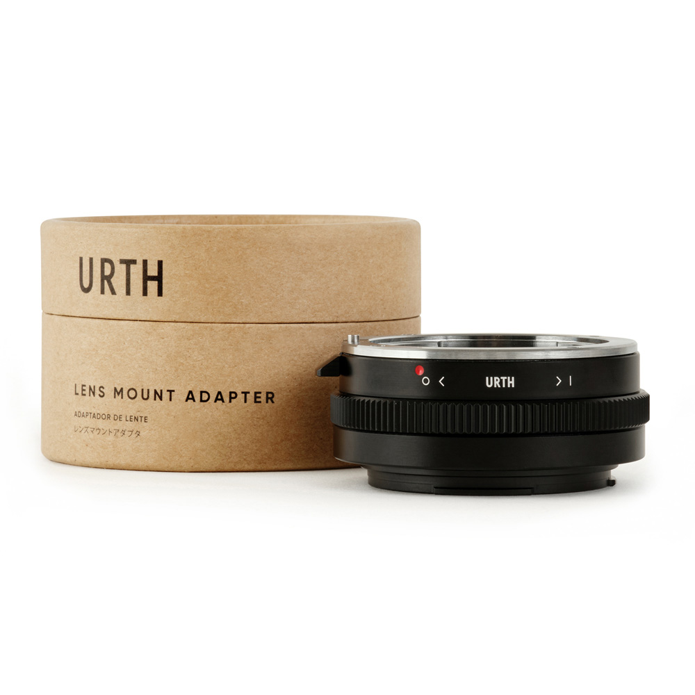 Musta Urth Sony A (Minolta AF) - Canon RF objektiiviadapteri istuu vieressä sen lieriömäinen pahvipakkaus merkitty URTH LENS MOUNT ADAPTER valkoisella taustalla.