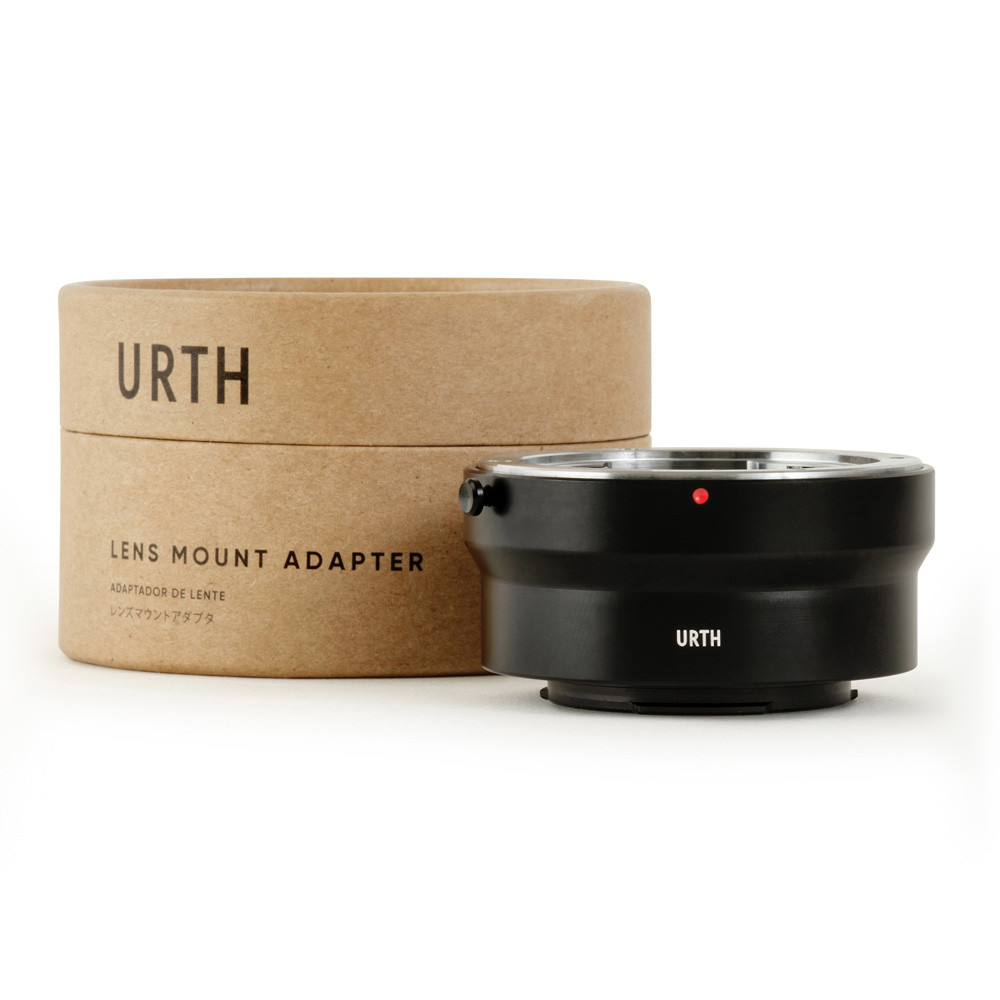 Musta Urth Contax/Yashica (C/Y) - Fujifilm X objektiiviadapteri näkyy sen pyöreän, ruskean pahvisen pakkauksen vieressä, jossa lukee Urth Lens Mount Adapter.