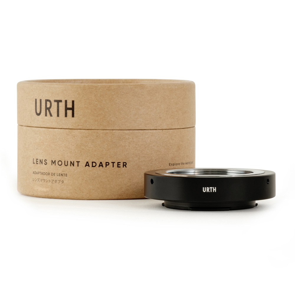 Musta Urth M39 - Fujifilm X objektiiviadapteri näkyy sen lieriömäisen, ruskean pahvilaatikon vieressä, jossa lukee Urth Lens Mount Adapter.