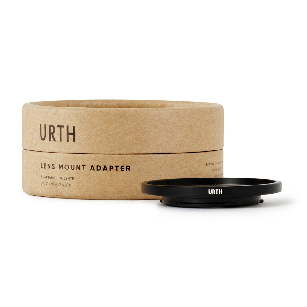 The Urth C Mount - Micro Four Thirds (M4/3) Lens Mount Adapter is displayed next to a cylindrical, eco-friendly cardboard box with the URTH Lens Mount Adapter labeled on a white background.