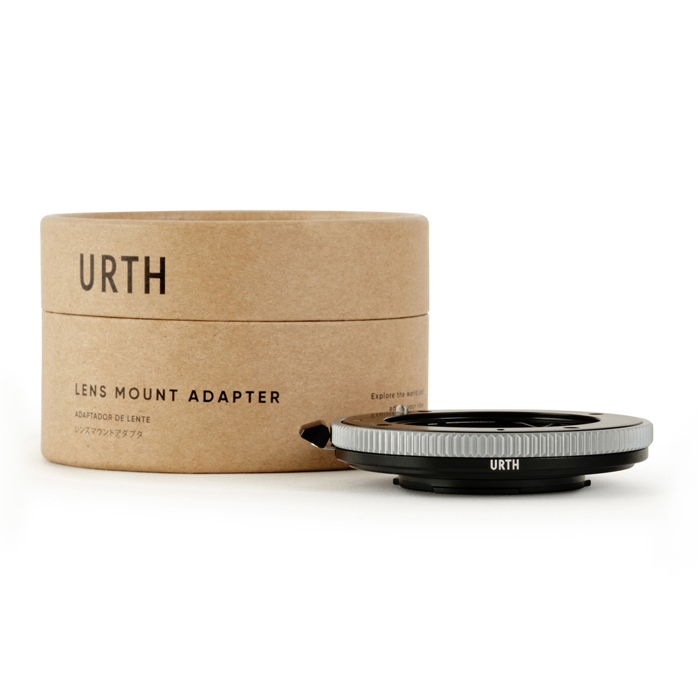 A cardboard box with the words "Urth Contax G - Micro Four Thirds (M4/3) lens adapter" is next to the black and silver camera lens mount adapter on a white background.