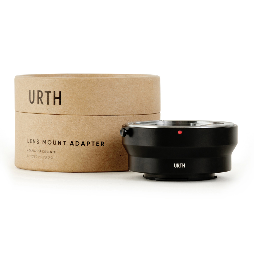 The black Urth Contax/Yashica (C/Y) - Micro Four Thirds (M4/3) Lens Mount Adapter is displayed next to its cylindrical cardboard box, which is marked URTH Lens Mount Adapter on a white background.