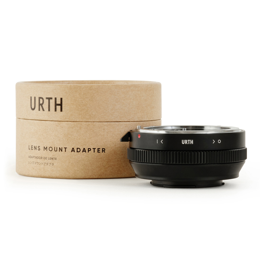 Musta Urth Nikon F (G-tyyppi) - Micro Four Thirds (M4/3) objektiiviadapteri näkyy sen sylinterimäisen pahvipakkauksen vieressä, jossa on merkintä "Lens Mount Adapter" valkoisella pohjalla.