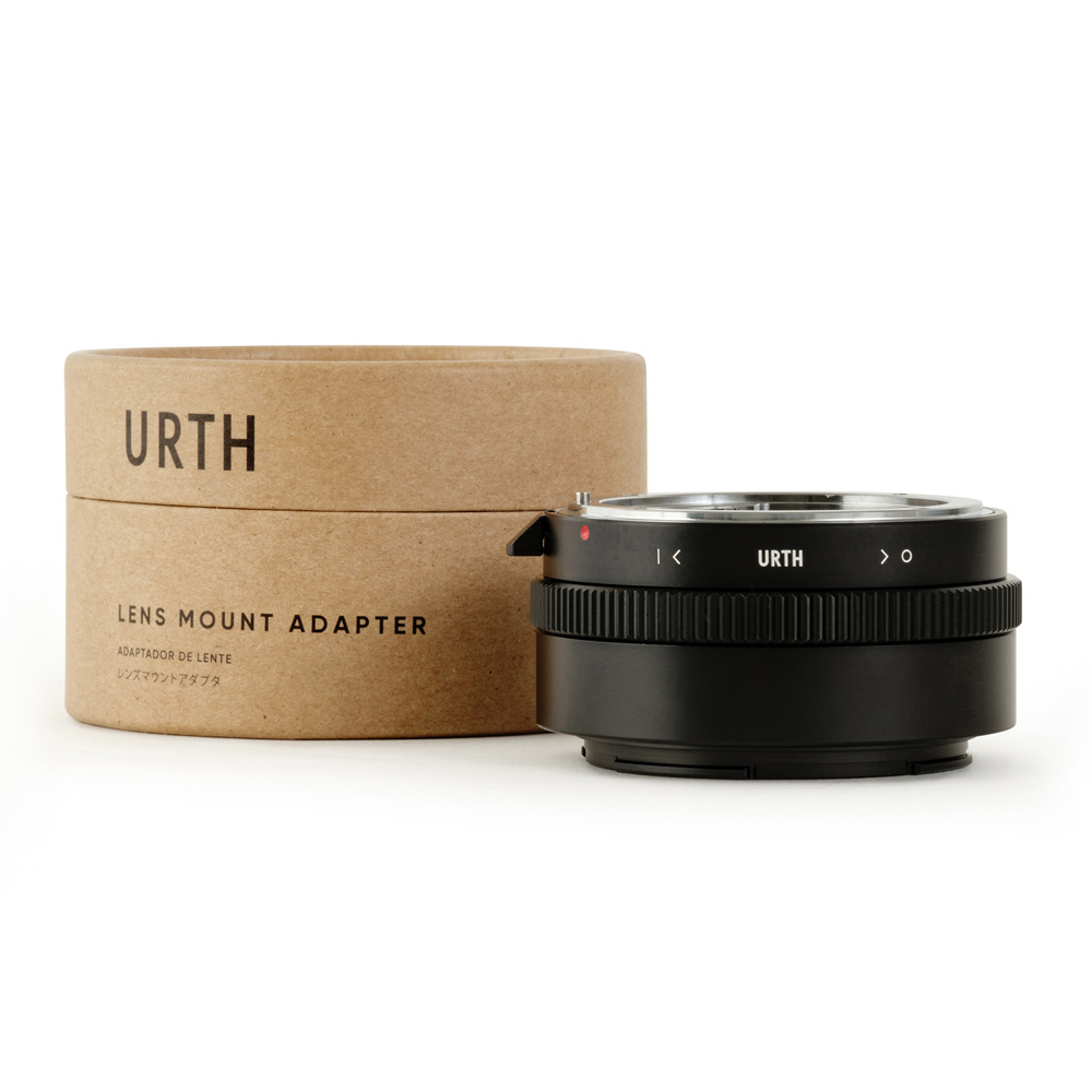 Urth Nikon F (G-tyyppi) - Nikon Z objektiiviadapteri istuu sen pyöreä, ruskea pahvilaatikko merkitty "Lens Mount Adapter" Englanti ja Japani. Mustassa sovittimessa on harjanteet ja Urth-logo.