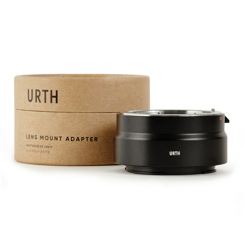 Musta Urth Pentax K - Nikon Z objektiiviadapteri istuu sen lieriömäisen ruskean pahvilaatikon vieressä, jossa lukee "Urth Lens Mount Adapter" valkoisella pohjalla.