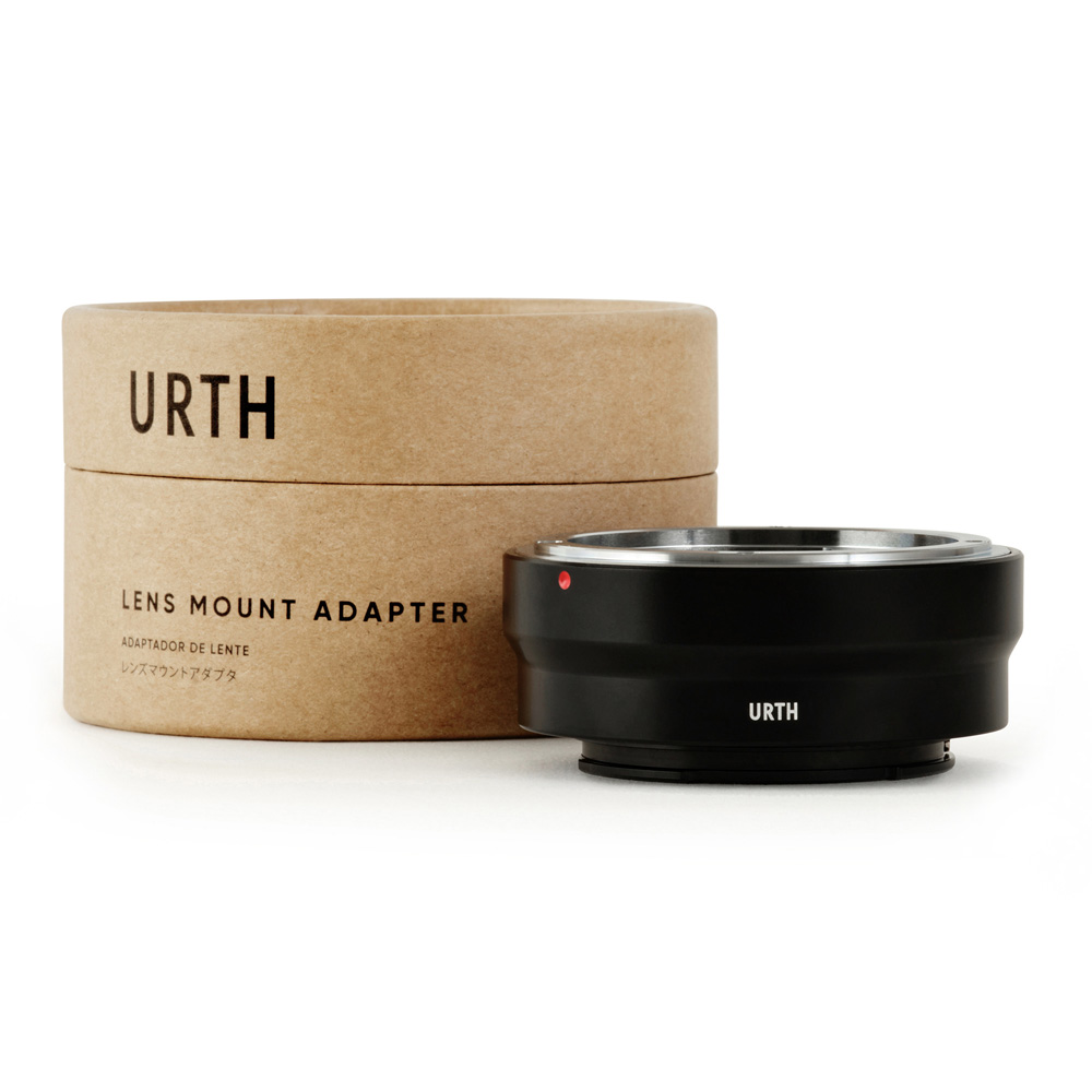 Musta Urth Konica AR - Sony E objektiiviadapteri näkyy sen pyöreän, ruskean pahvisen pakkauksen edessä, jossa lukee "URTH Lens Mount Adapter". Adapterissa on metallinen reunus ja pieni punainen merkkipiste.
