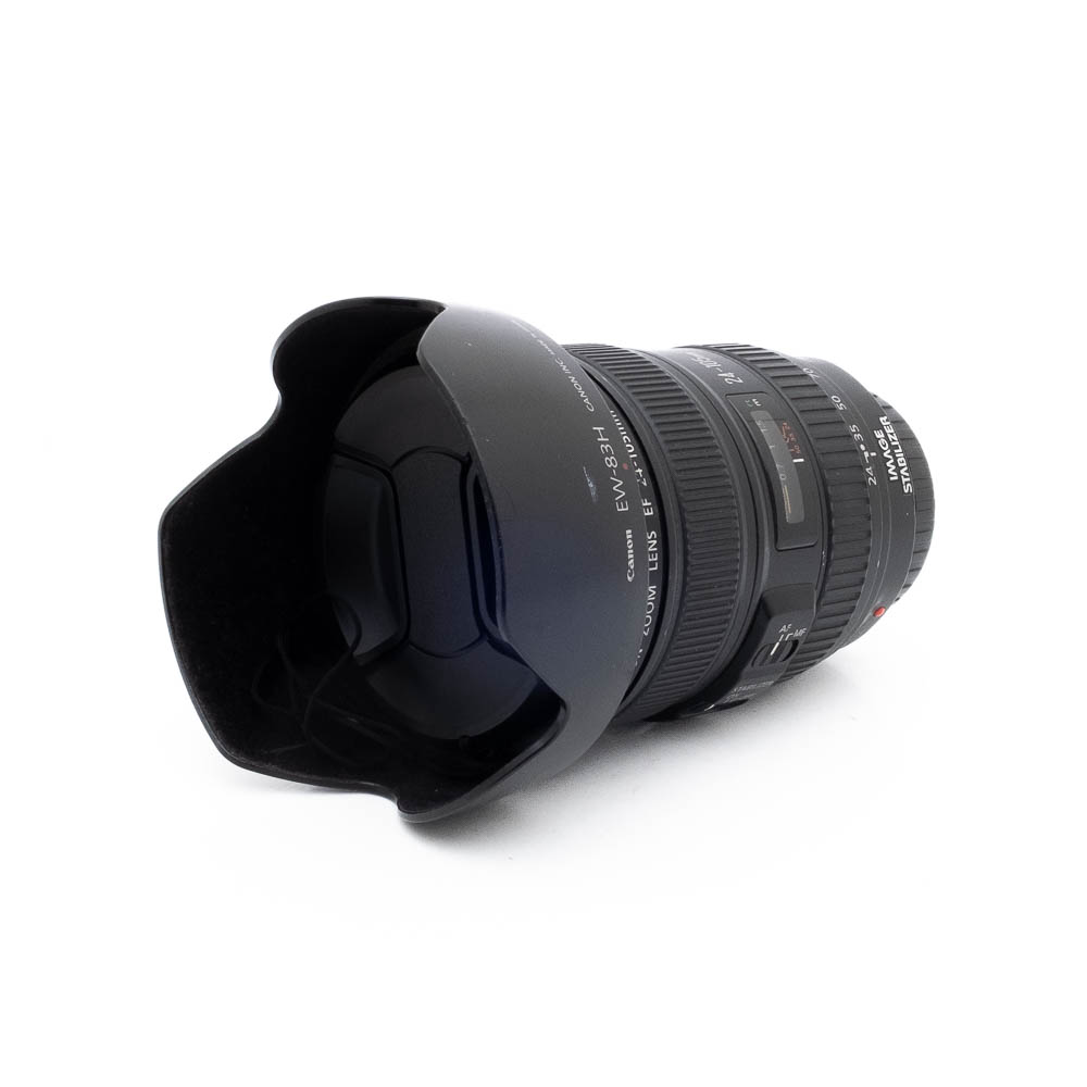 The Canon EF 24-105mm f/4 L IS USM lens (used), with a petal-shaped cap attached, rests on its side against a white background.