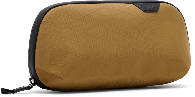 Peak Design Tech Pouch Small - Coyote is a tan rectangular travel pouch with a diamond pattern, black zipper, black trim and a small black logo tag in the upper right corner.