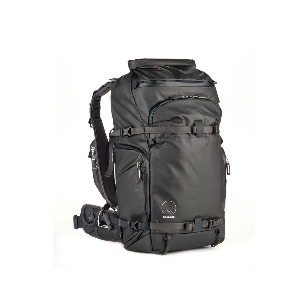 Shimoda30v2_1 Shimoda Action X30 v2 Backpack - musta -kamerareppu on suuri musta reppu, jossa on useita lokeroita, vetoketjutaskut, säädettävät hihnat, lantiovyö ja pieni valkoinen logo, joka on suunniteltu matkoille tai ulkokäyttöön ja jossa on tyylikäs ja kestävä rakenne.