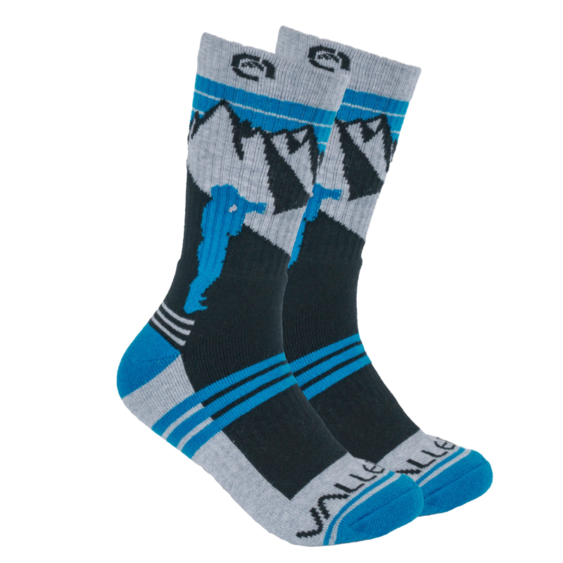 Vallerret Merino Wool Crew Sock - Mtn Blue (36-40) -sukissa on mustan, harmaan ja sinisen värinen vuoristomaisema, siniset kantapäät ja varpaat sekä kiipeilijän siluetti sivulla.