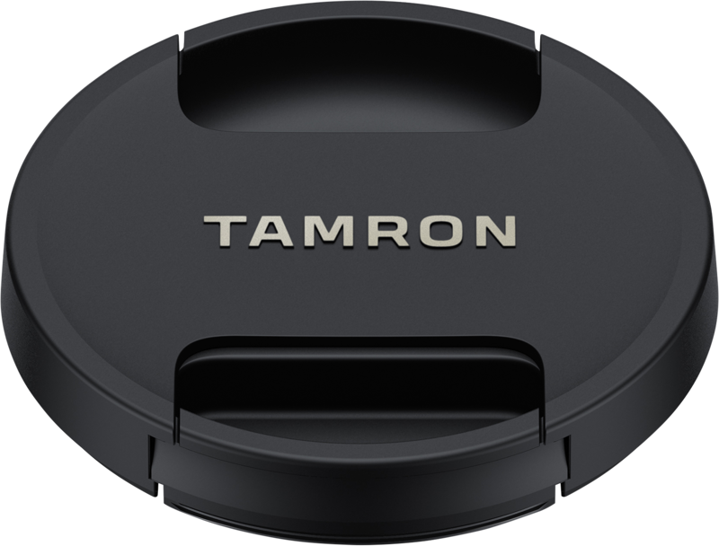 Tamron Lens Cap 67mm on musta suojus, jonka keskellä on hopeisilla kirjaimilla kirjoitettu "TAMRON" ja jossa on pidikkeet kameran objektiiviin kiinnittämistä varten.