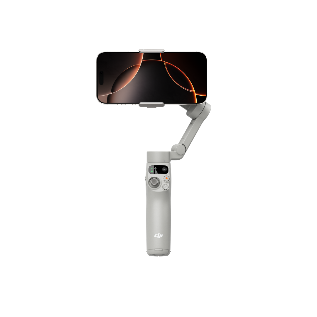 Älypuhelin on kiinnitetty harmaaseen DJI Osmo Mobile 7 -gimbaali kännykälle käsikäyttöiseen gimbal-stabilisaattoriin valkoista taustaa vasten. Puhelimen näytöllä on tumma taustakuva, jossa on oransseja kaarevia viivoja.