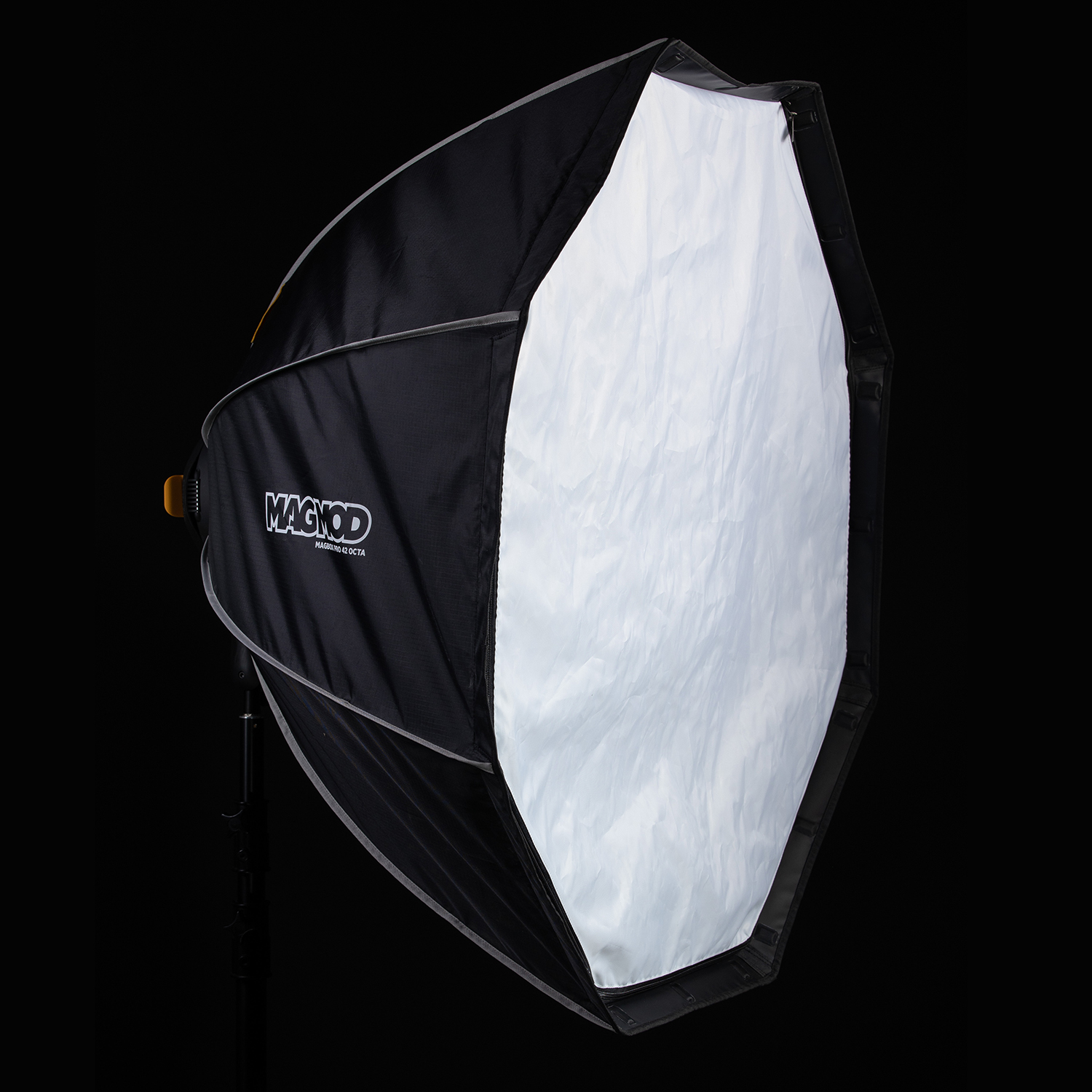 MagMod MagBox Pro 42 Octa, suuri kahdeksankulmainen softbox, jossa on valkoinen diffuusoripaneeli ja mustat sivut, asennettuna jalustalle mustaa taustaa vasten. MagModin logo on näkyvissä sen kyljessä.