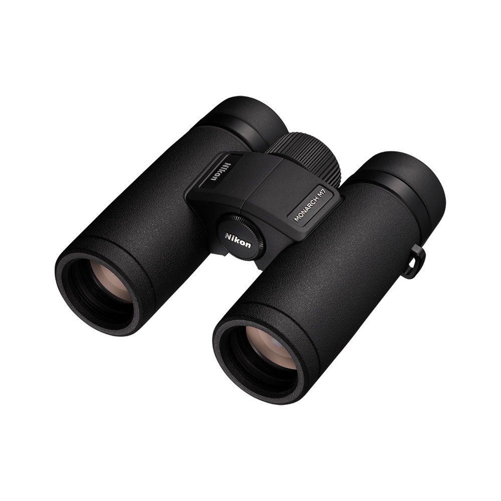Nikon Monarch M7 10x30 -kiikarit, mustat, kuvioiduilla kahvoilla varustetut kiikarit, joiden etulinssit ja keskitarkennuksen nuppi näkyvät valkoista taustaa vasten.