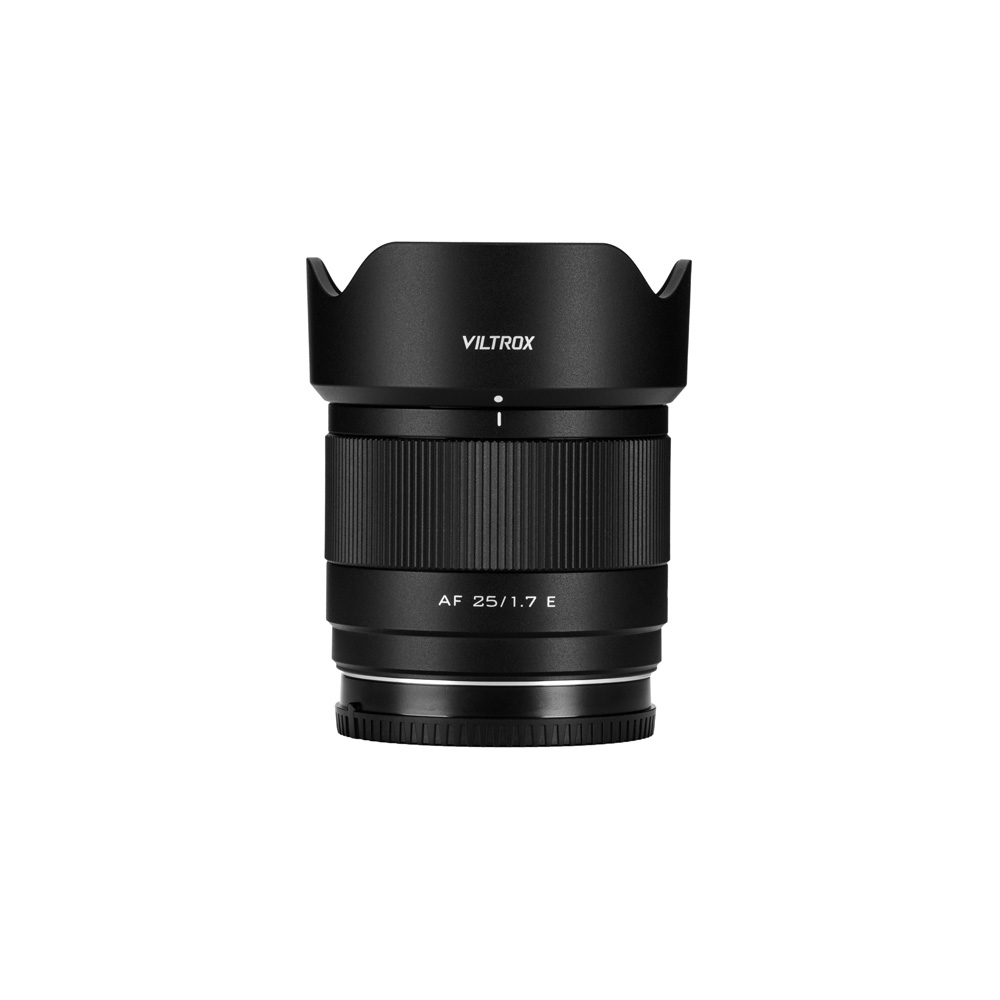 Musta Viltrox AF 25mm F/1.7 -objektiivi, Sony E, jossa on vastavalosuoja kiinnitettynä, seisoo pystyssä valkoista taustaa vasten.