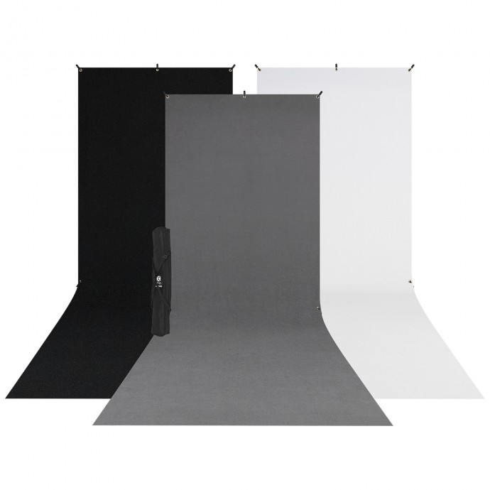 Westcott X Drop 3 Pack Sweep Backdrop Kit (1.5m x 3.7m) sisältää mustat, harmaat ja valkoiset taustat, jotka on asetettu vierekkäin ja joissa on loiva pohjan kaari ja taitettu kolmijalkainen jalusta mustan taustan edessä.