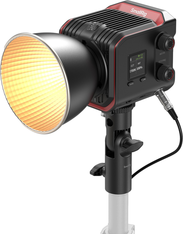 SMALLRIG 5142 RC 100B COB LED Video Light Pro Version -valaisimessa on suuri harjattu heijastin, digitaalinen näyttö ja se on asennettu mustaan jalustaan. Kun valaisin kytketään päälle, se säteilee lämmintä valoa ja näyttää SmallRig-merkin.