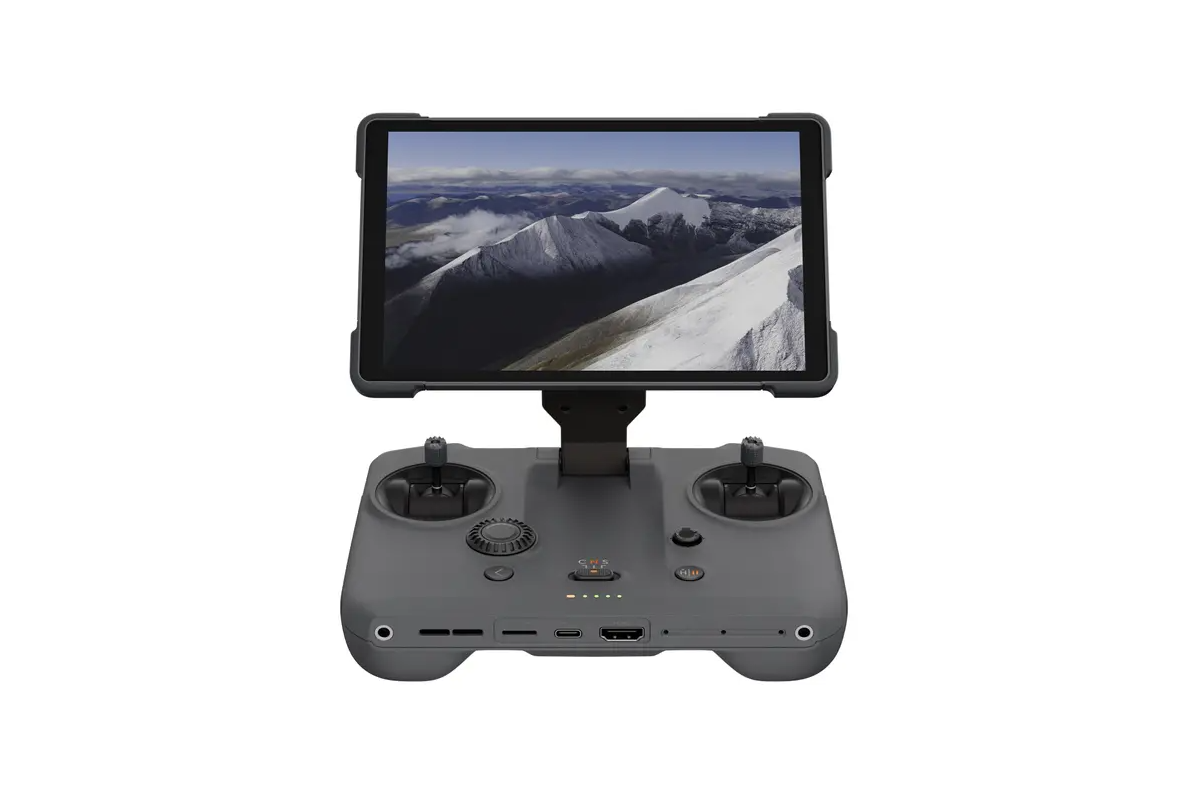 DJI RC Pro 2 -ohjain on harmaa kauko-ohjain, jossa on kaksi joystickiä ja asennettu näyttö, jossa näkyy luminen vuoristomaisema edestä valkoista taustaa vasten.