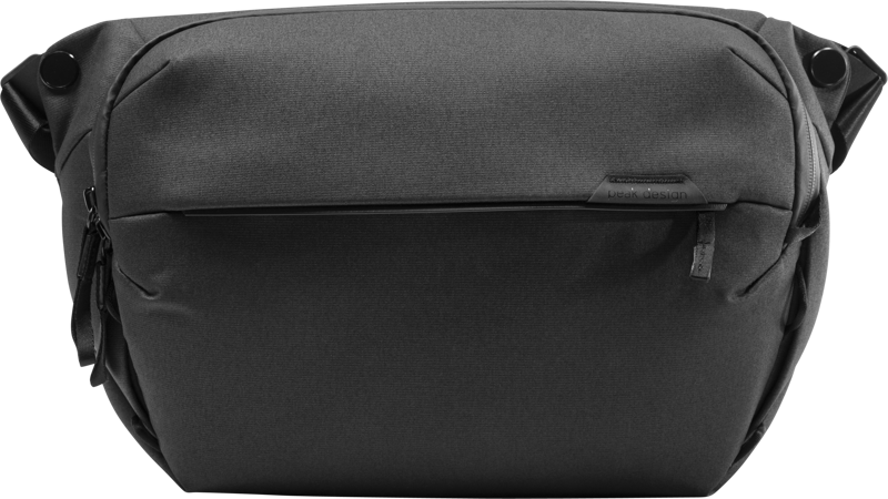 Mustassa Peak Design Everyday Sling 10L v2 -rinkassa on moderni läpällinen muotoilu, vetoketjullinen etutasku ja säädettävät hihnat, jotka näkyvät yksiväristä taustaa vasten.