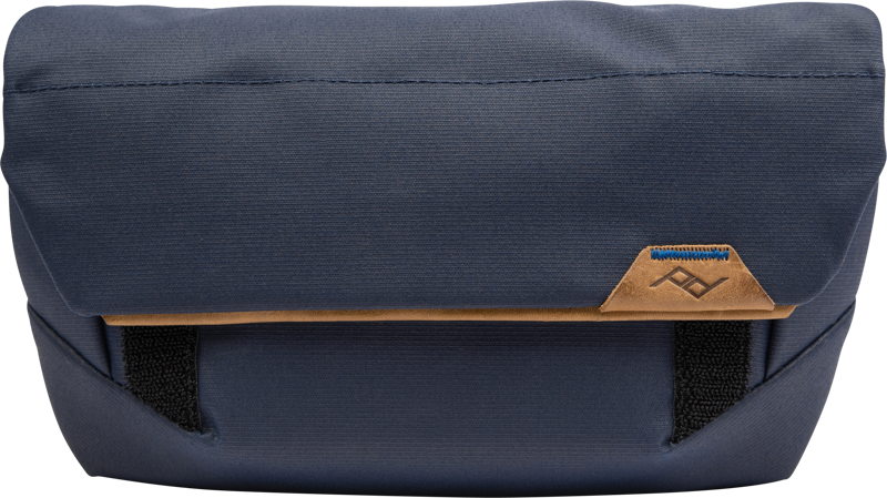 Peak Design The Field Pouch v2 // Midnight is a rectangular navy blue pouch with tan leather accents, black straps and a small stitched logo on the front.
