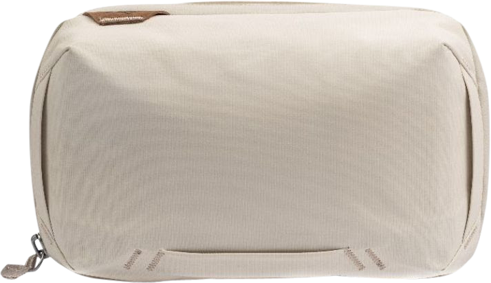 Peak Design Tech Pouch // Bone on beige suorakulmainen kangaspussi, jossa on vasemmanpuoleinen vetoketju, pieni ruskea lappu vasemmassa yläkulmassa ja hienovaraiset tikkaukset lähellä pohjaa.
