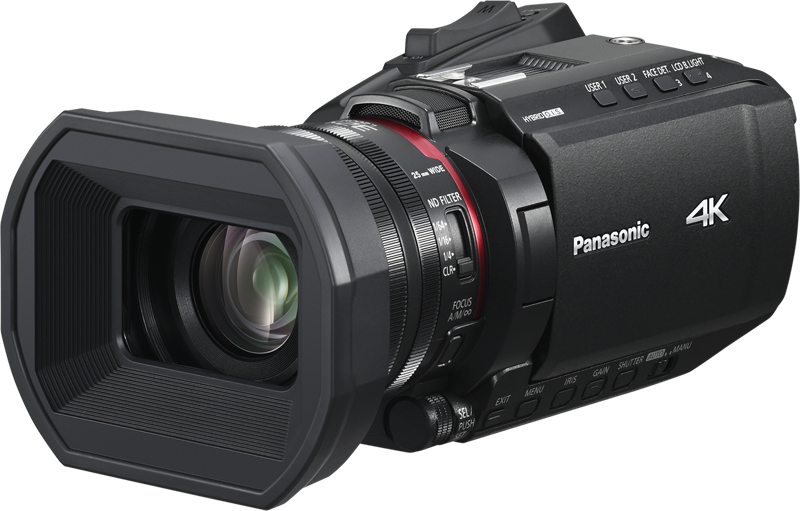 Musta Panasonic HC-X1200E 4K-videokamera, jossa on suuri linssinsuojus, sivussa olevat ohjauspainikkeet ja näkyvä linssi, on kuvattu kolmivartalokulmasta tavallisella taustalla.