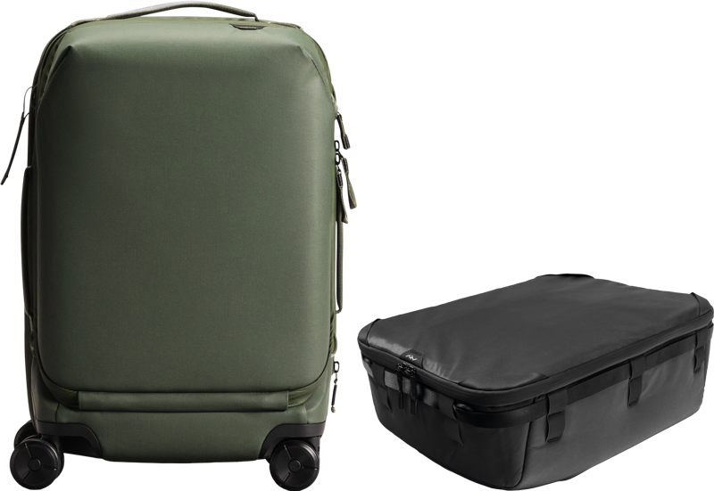 Vihreä Peak Design Roller Pro Carry-On seisoo pystyssä mustan Camera Cube V2 X-large -kamerakuution vieressä, ja molemmat on sijoitettu vaalealle taustalle.
