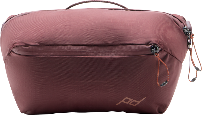 The Peak Design Outdoor Sling 4L Eclipse is a brown and yellow rectangular travel bag with a zip closure, small carry handle and a subtle PD logo on the bottom right corner.