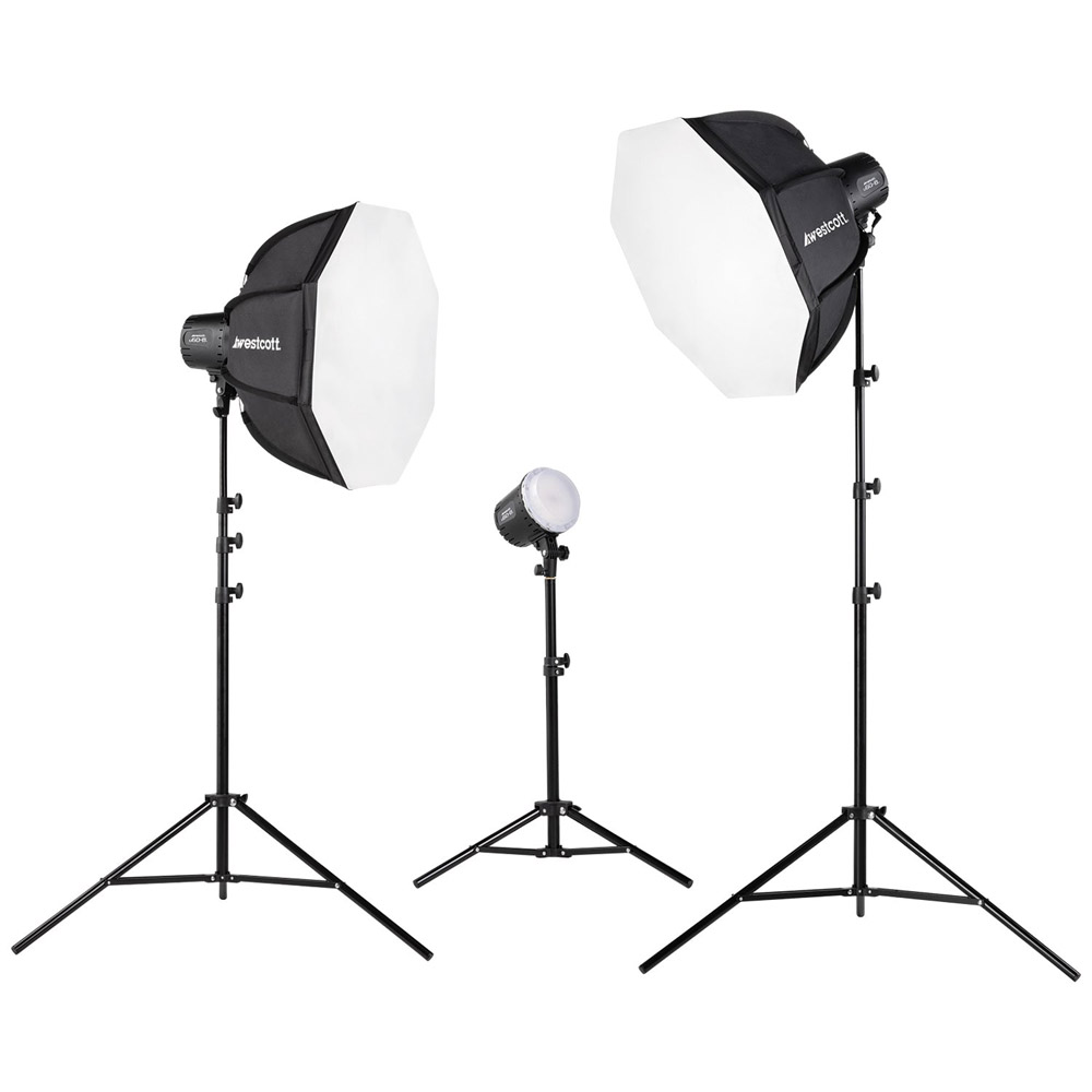 Westcott U60-B Bi-Color LED 3-Light Softbox Kit sisältää kolme studiovaloa jalustoilla: kaksi suurta valkoista softboxia kummallakin puolella ja yksi paljaalla lampulla keskellä, kaikki valkoista taustaa vasten.