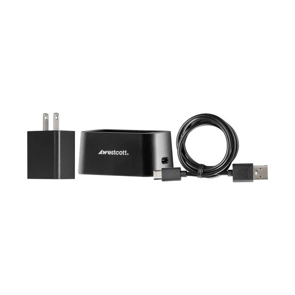 Westcott FJ80-SE -akkulaturi ja -johto, jossa on musta latausdokkari, USB-kaapeli ja seinäsovitin, ovat vierekkäin valkoisella pohjalla.