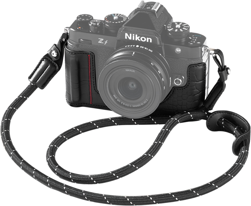 Nikon Z f, jossa on musta SmallRig 5095 -nahkakotelosarja, kiinnitetty objektiivi ja musta-valkoinen kuvioitu kaulahihna, joka on kiedottu eteen.