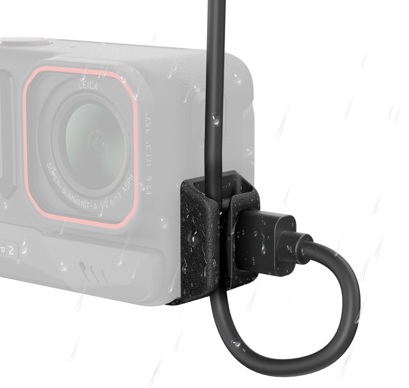 Lähikuva Insta360 All-Weather USB Charging Cover Ace Pro 2/Ace Pro -liitinsuojasta, jonka kaapelissa ja liittimessä on vesipisaroita, mikä korostaa sen vedenkestävää rakennetta. Kameran linssi ja runko näkyvät hieman epäselvästi taustalla.