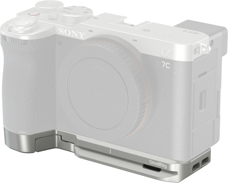 Hopeanvärinen Sony Alpha 7C -kamera, jossa on objektiivin suojus, on kiinnitetty SmallRig 5482 Pohjalevy AirTag-paikalla Sony A7C II / A7CR Hopea -laitteeseen, kuvattuna etupuolelta vaaleaa taustaa vasten.