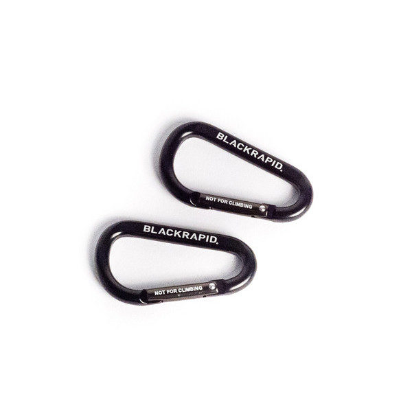Kaksi mustaa BlackRapid CarabineR (2 kpl) -karabinettia, joissa on merkinnät "BLACKRAPID" ja "NOT FOR CLIMBING", lepäävät samansuuntaisesti valkoisella pinnalla.