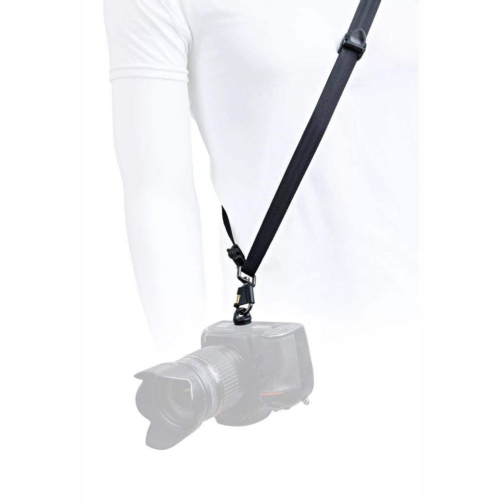 Valkoiseen paitaan pukeutunut henkilö käyttää BlackRapid Blackline I Right Camera Sling-kamerahihnaa, jossa DSLR-kamera roikkuu hänen vierellään. Tausta on valkoinen ja kuvan alaosa on häivytetty.