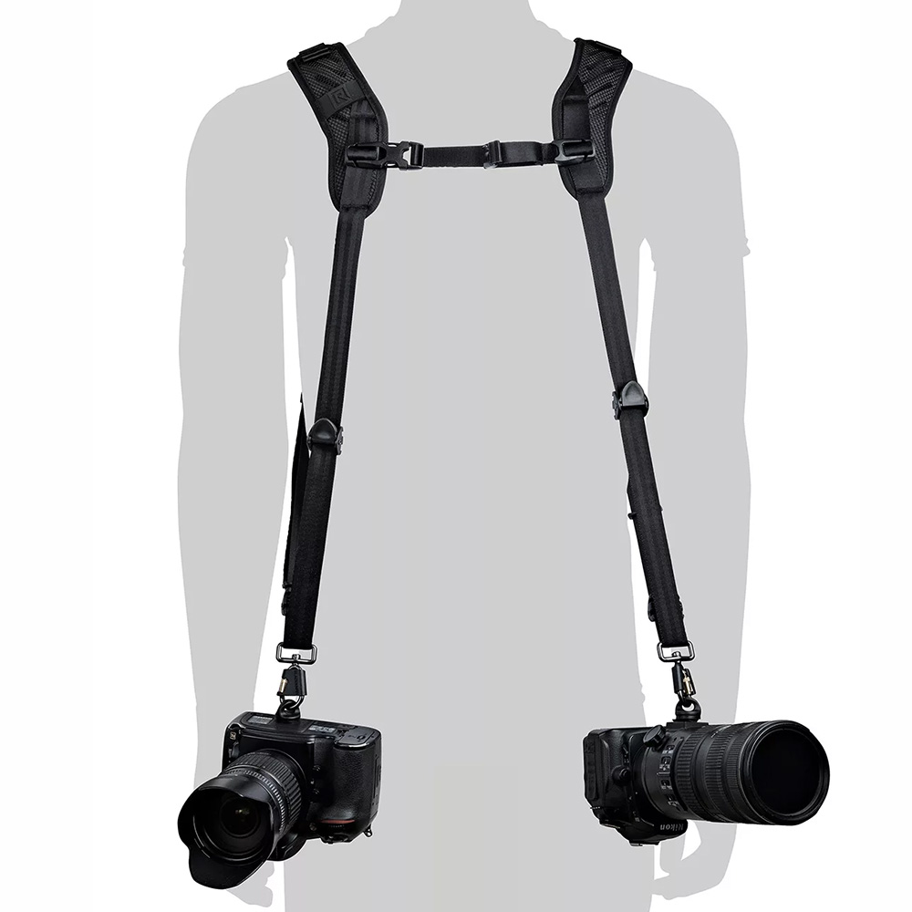 Siluetti henkilöstä, jolla on BlackRapid Blackline II Double Camera Harness -kamerahihna ja joka kantaa kahta mustaa DSLR-kameraa lantion korkeudella, yksi kummallakin puolella.