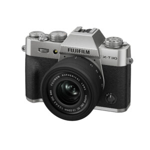 Hopeinen Fujifilm X-T30 III, jossa on XC 13-33mm f/3.5-6.3 OIS -objektiivi, on kuvattu niin, että kameran rungon ja objektiivin etu- ja vasen puoli on näkyvissä.