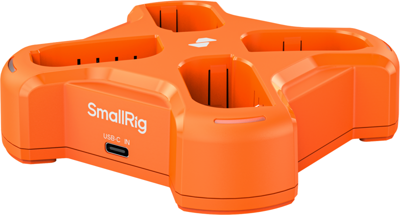 Vaalealla taustalla näkyy oranssi SmallRig 5748 nelikanavainen akkulaturi, jossa on neljä paikkaa ja sivussa USB-C IN -merkintä, joka on tarkoitettu akkujen lataamiseen.